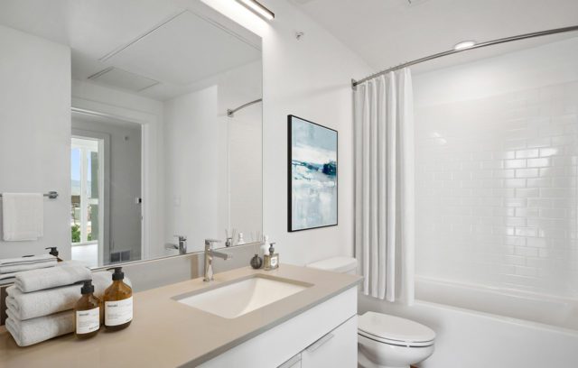 Model bathroom with white vanity and large mirror
